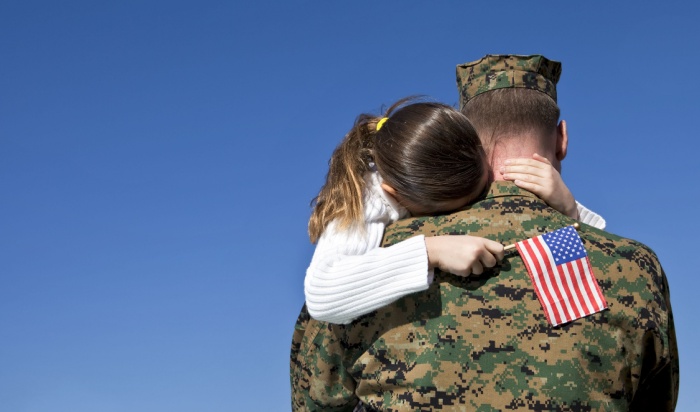 Soldier carrying his daughter holding american flag.